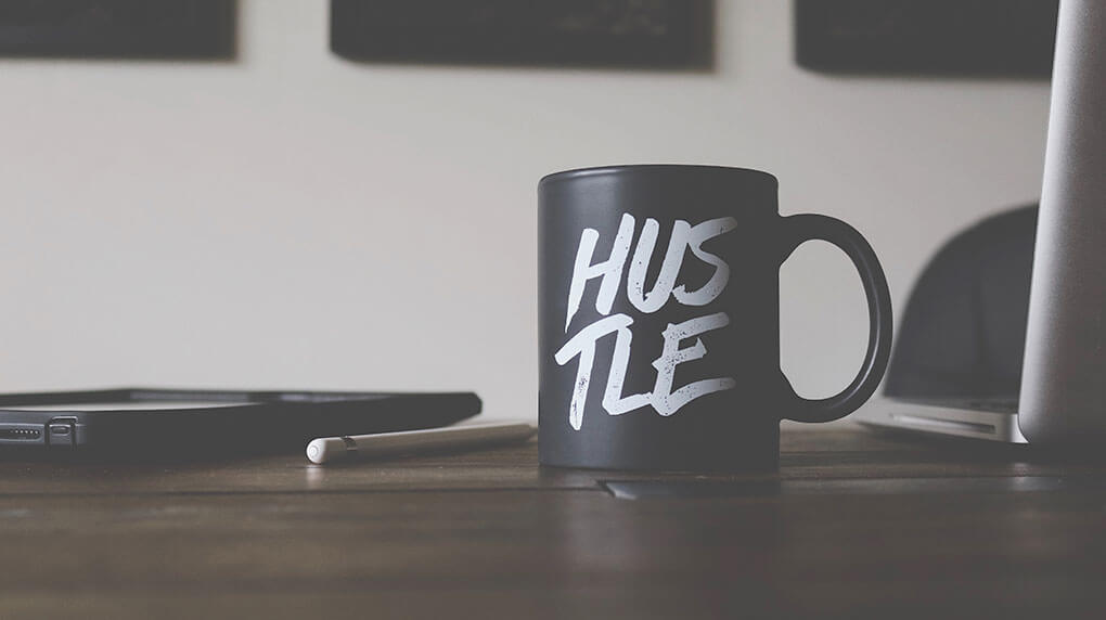 black mug with text Hustle on the desk